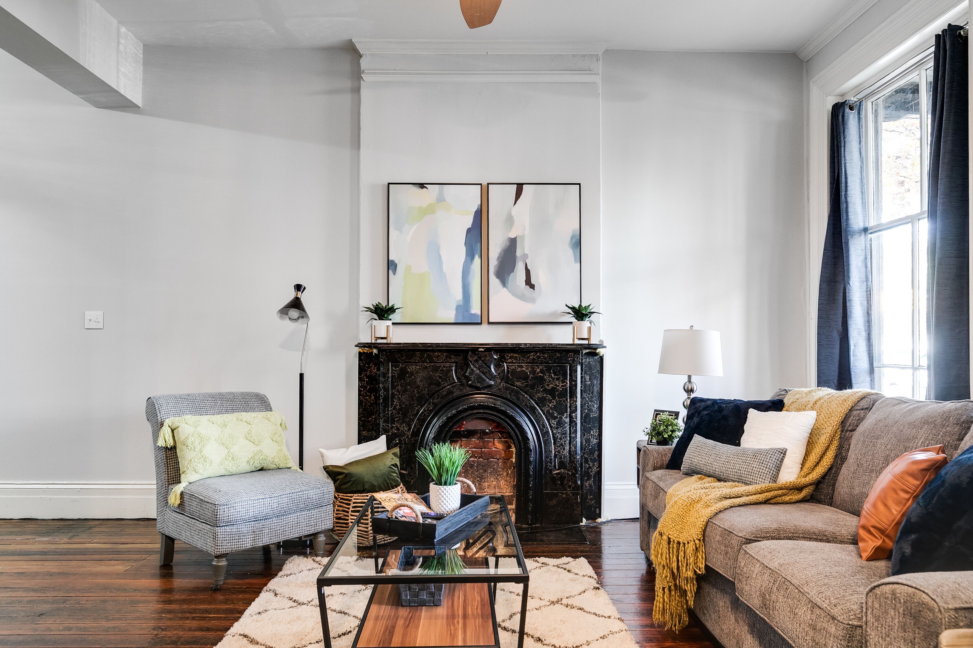 A living room with a fireplace, a sofa, a chair, and abstract art on the wall.