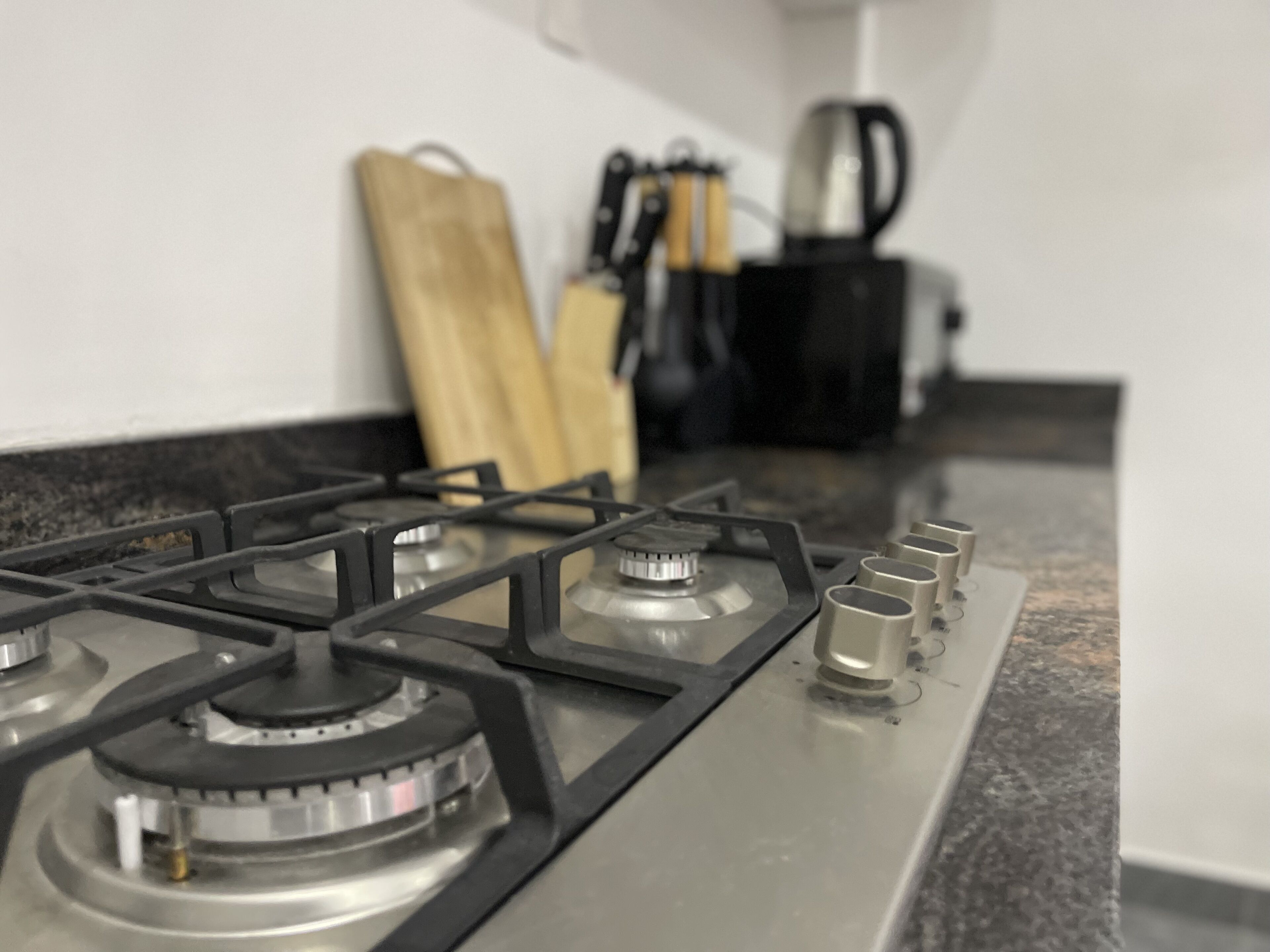 A kitchen with a gas stove, a coffee maker, and a knife block.