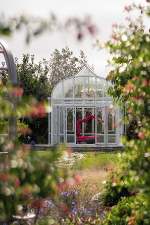 A greenhouse with a curved roof, a pink chair, and a small table.