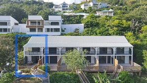 Un edificio moderno de dos pisos con techo plano, varios balcones y una terraza de madera.