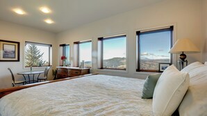 A bedroom with a large bed, multiple windows, a desk, and a chair. - Stunning 360 Ocean Views, Near Redwoods NP! (Smith River)