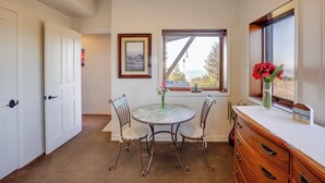 A room with a round table, two chairs, a dresser, and a window with a view. - Stunning 360 Ocean Views, Near Redwoods NP! (Smith River)