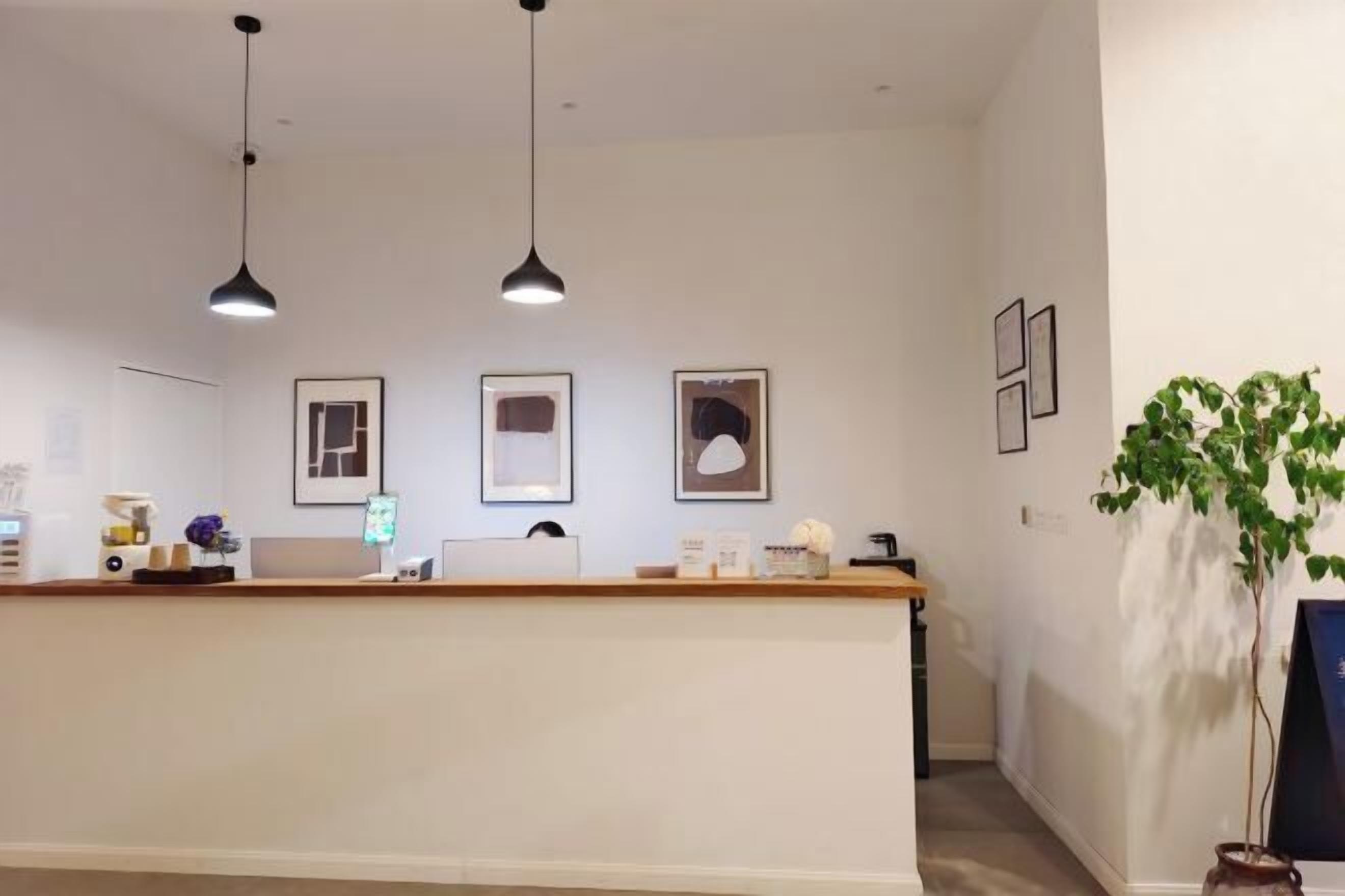 A reception area with a wooden counter, framed artwork on the wall, and pendant lighting.