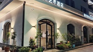 Fachada de hotel moderna, con ventanas arqueadas y plantas en macetas.