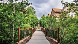 A pathway leading to a building with a stone entrance, surrounded by trees and a wooden fence.