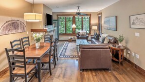 A spacious living room with a wooden dining table, leather sofa, and a fireplace.