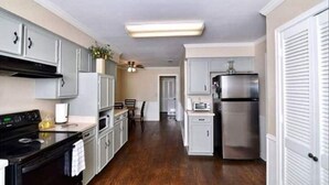 Una cocina moderna con armarios blancos, electrodomésticos de acero inoxidable y piso de madera.