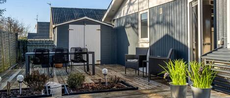 A patio with a table and chairs, a small shed, and potted plants.