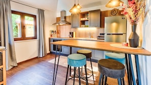 Een moderne keuken met houten aanrecht, barkrukken en hanglampen.