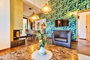 Experience the warm and inviting atmosphere of our lobby, featuring a comfortable seating area with a sofa and chairs, a marble reception desk, and a large flat-screen TV.