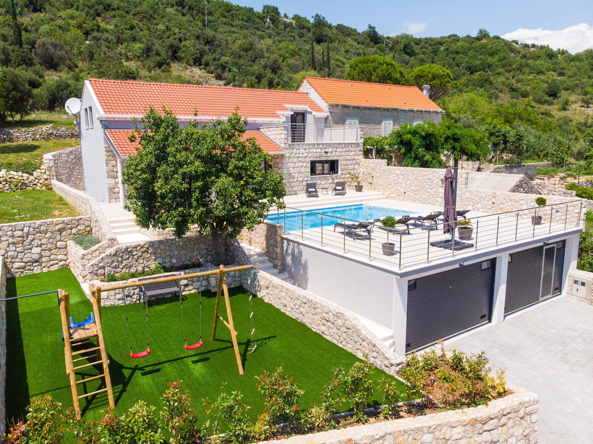 A modern villa with a swimming pool, stone walls, and a garden.