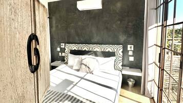 Un dormitorio moderno con cama, ventilador de techo, ventana grande y armario de madera.