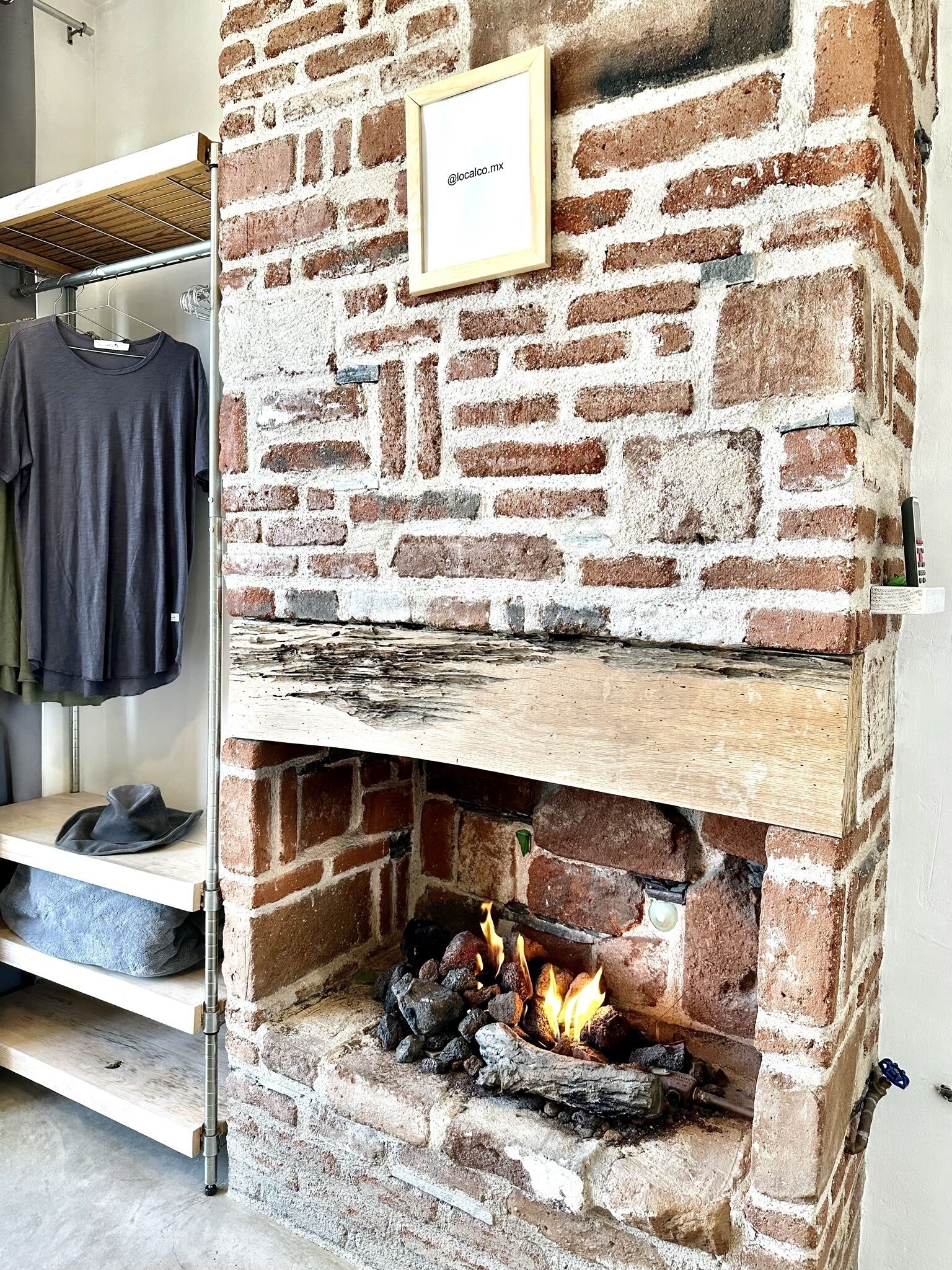 A brick fireplace with a metal shelf above it and a framed sign with a handle.