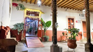 Une cour intérieure abritée, dotée d’un plafond en bois, d’une entrée décorative et de plantes en pot.