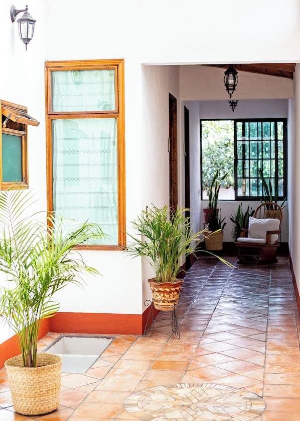 A hallway with tiled flooring, a wooden bench, and potted plants. - Posada El Palomar Pátzcuaro (Patzcuaro)