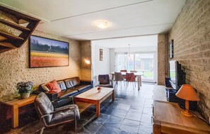 A living room with a sofa, chairs, a coffee table, a TV, and a painting on the wall. - Amazing home in Callantsoog with WiFi (Callantsoog)
