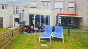 Une cour avec un espace patio, des sièges extérieurs et un bâtiment à la façade en briques.