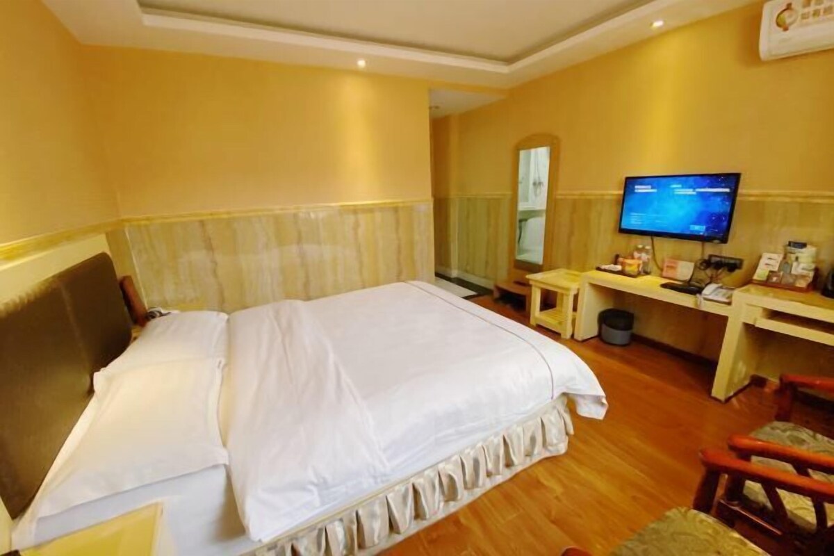Une chambre d’hôtel équipée d’un lit, d’un bureau, d’une chaise, d’une télévision et d’une poubelle.