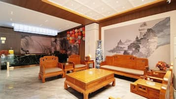 Um hall com mobiliário de madeira tradicional, uma mesa de recepção e um mural.