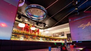 Un área de bar moderna con una pantalla LED circular, asientos cómodos e iluminación ambiental.