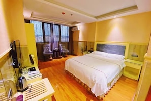 A hotel room with a bed, a desk with a computer, a chair, and a TV.