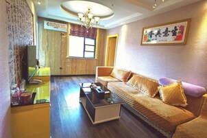 Una sala de estar con un sofá, una mesa de centro, un televisor y una ventana con cortinas.