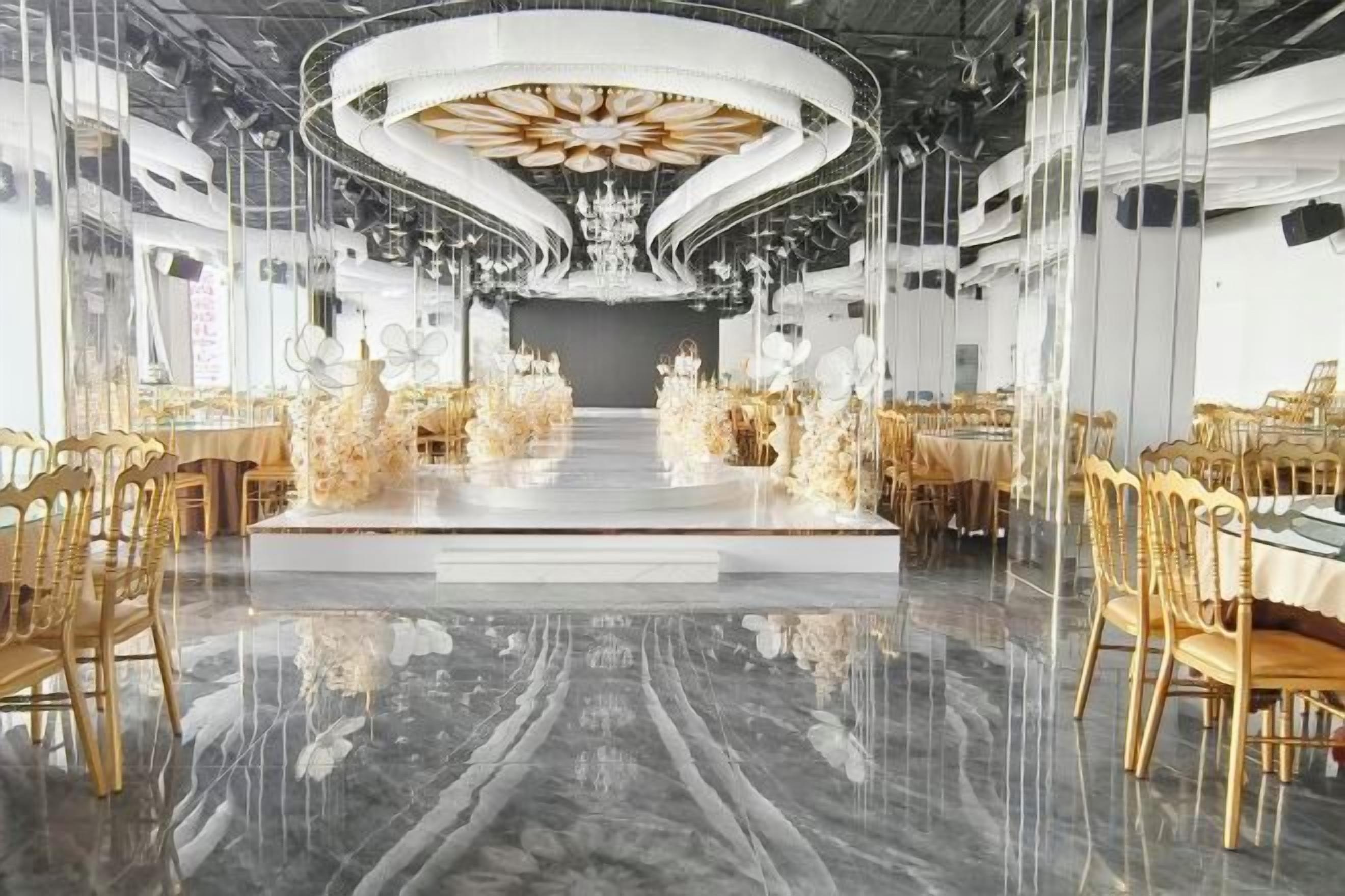A spacious hall with a central stage, surrounded by tables and chairs, and a reflective floor.