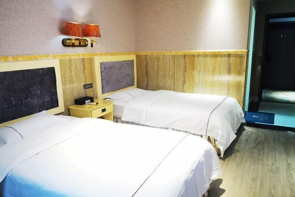 Une chambre d’hôtel avec deux lits, une table de chevet, une lampe et une porte donnant sur une salle de bain.