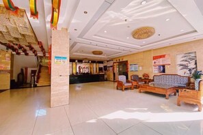 Un hall d’hôtel comprenant un comptoir d’accueil, un espace salon et un escalier.