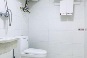 Une salle de bain avec des toilettes, un lavabo et une douche.