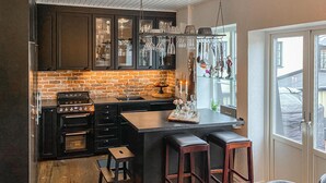 A kitchen with dark cabinetry, a brick backsplash, and a central island with stools. - 2 bedroom nice home in Ystad (Ystad)