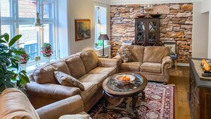 A cozy living room with leather sofas, a stone wall, and a dining area with a table set for two. - 2 bedroom nice home in Ystad (Ystad)