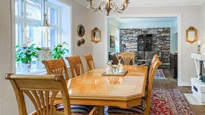 A dining room with a wooden table and chairs, a chandelier, and a stone fireplace. - 2 bedroom nice home in Ystad (Ystad)