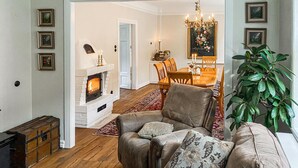 A cozy living room with a fireplace, a dining area with a chandelier, and a large green plant. - 2 bedroom nice home in Ystad (Ystad)