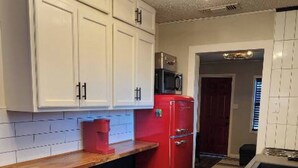 A kitchen with white cabinets, a red refrigerator, a wooden countertop, and a stainless steel trash can. - Cozy & Convenient Bungalow - Downtown & HPU (Brownwood)