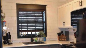 A kitchen with white cabinets, a black countertop, a stainless steel sink, a black stove, and a patterned rug. - Cozy & Convenient Bungalow - Downtown & HPU (Brownwood)