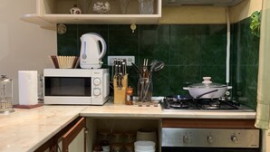 Uma cozinha compacta com micro-ondas, fogão, forno e diversos utensílios.