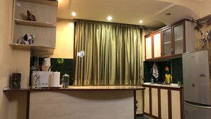 Uma cozinha compacta com geladeira embutida, cafeteira e uma estante com objetos decorativos.
