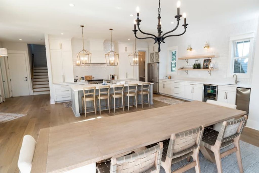 A spacious kitchen with a large island, pendant lighting, and white cabinetry.