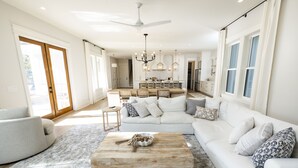 Ein geräumiges Wohnzimmer mit einem weißen Sofa, einem Holztisch und einer Kristallleuchter.