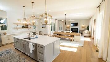 A spacious kitchen with a large island, pendant lighting, and a dining area with a round table.