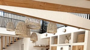 Una cocina moderna con una isla grande, detalles de madera y lámparas colgantes de mimbre.