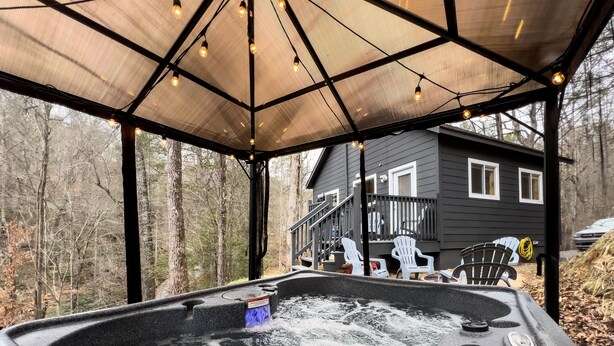A hot tub with a wooden deck and a covered area with string lights. - Romantic Retreat • Hottub, Gazebo, Firepit, ~Game,Kayak, Lake access & Fishing (Sevierville)