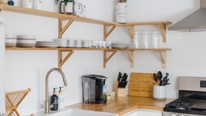 Una cocina con estantes de madera, una cafetera y una estufa.