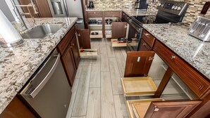 Eine Küche mit Holzschränken, Granit Arbeitsplatten und Edelstahlgeräten.