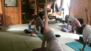 A yoga class in a room with wooden walls and a carpeted floor.
