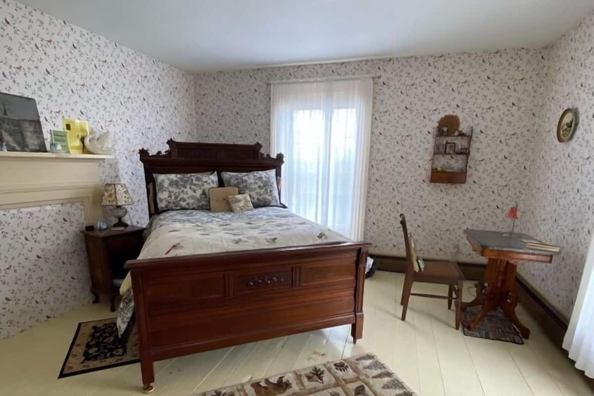 A bedroom with a wooden bed, a nightstand, a chair, a small table, and a rug with animal prints.