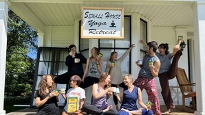 A group of people on a porch with a sign that reads "Seawall House Yoga Retreat".