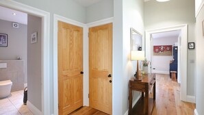 A hallway with wooden doors, a small table with a lamp, and a mirror on the wall.