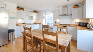 A modern kitchen with white cabinets, wooden dining table, and chairs.